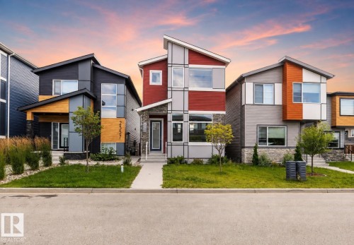 Modern architectural style with a multi-level roofline, prominent red and gray paneling, and an inviting entryway with a glass-paneled door - 2355 Kelly Circle Circle Sw, Edmonton, AB - Outdoor With Facade