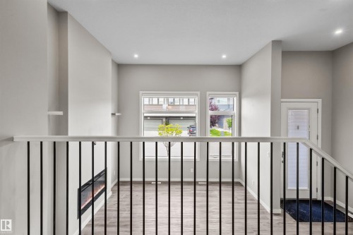 Open-concept layout with wood-finish flooring, a linear electric fireplace, and a white front entry door with frosted glass paneling - 2355 Kelly Circle Circle Sw, Edmonton, AB - Indoor Photo Showing Other Room