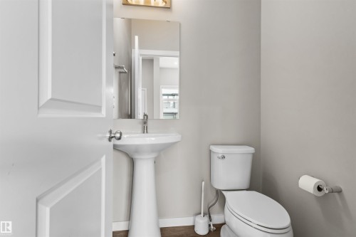 Pedestal sink with a polished chrome faucet, rectangular mirror, and a white toilet - 2355 Kelly Circle Circle Sw, Edmonton, AB - Indoor Photo Showing Bathroom