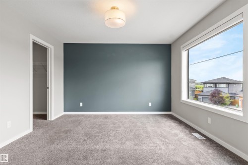 Expansive window, accent wall, flush mount ceiling fixture, gray carpet, and closet with built-in shelving - 2355 Kelly Circle Circle Sw, Edmonton, AB - Indoor Photo Showing Other Room