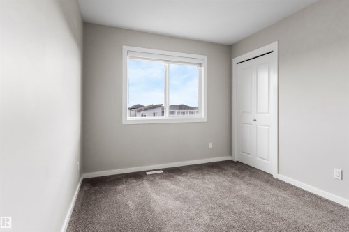 Neutral painted walls, white trim, window with white frame, bi-fold closet door, and gray carpet - 2355 Kelly Circle Circle Sw, Edmonton, AB - Indoor Photo Showing Other Room