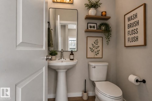 Pedestal sink with chrome faucet, wall-mounted rectangular mirror, and light wood-finish floating shelves - 2355 Kelly Circle Circle Sw, Edmonton, AB - Indoor Photo Showing Bathroom