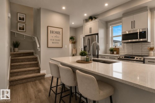 Kitchen island with seating, stainless steel appliances, recessed lighting, double basin sink, and wood-finish flooring - 2355 Kelly Circle Circle Sw, Edmonton, AB - Indoor Photo Showing Kitchen With Stainless Steel Kitchen With Double Sink With Upgraded Kitchen