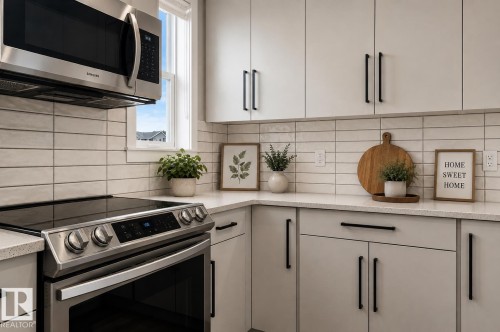Stainless steel range with a built-in microwave, light-toned cabinetry, light-toned horizontal tile backsplash, and light-toned countertops - 2355 Kelly Circle Circle Sw, Edmonton, AB - Indoor Photo Showing Kitchen