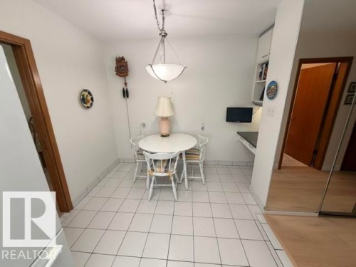 Eat-in kitchen area featuring white tile flooring, white walls, and a built-in desk with overhead cabinetry - 6824 89 Avenue Nw, Edmonton, AB - Indoor Photo Showing Dining Room