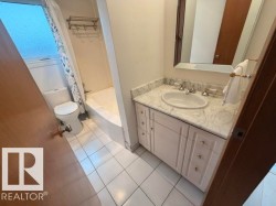 Bathroom featuring a white vanity with a stone countertop, an undermount sink, and a framed mirror - 