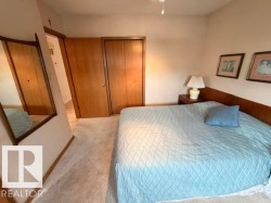 Bedroom featuring light-toned carpeting and wood-finish bi-fold closet doors - 