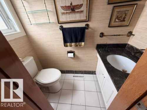Bathroom featuring a white vanity with a dark countertop, an undermount sink, and a white toilet - 6824 89 Avenue Nw, Edmonton, AB - Indoor Photo Showing Bathroom