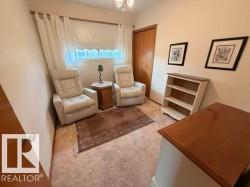 Carpeted room featuring a window with white window treatments, light beige walls, and a closet with wood-finish doors - 