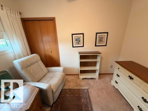 Carpeted room with a double-door closet featuring wood-finish paneling - 6824 89 Avenue Nw, Edmonton, AB - Indoor