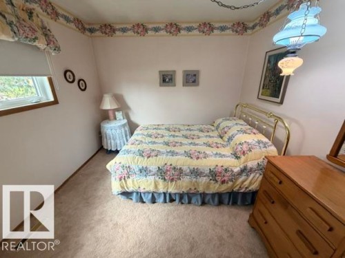 Carpeted interior space featuring a window with wood trim, a decorative ceiling light fixture, and a wallpaper border - 6824 89 Avenue Nw, Edmonton, AB - Indoor Photo Showing Bedroom