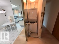 Dedicated laundry closet featuring a stackable washer and dryer, adjacent to light wood-finish flooring - 
