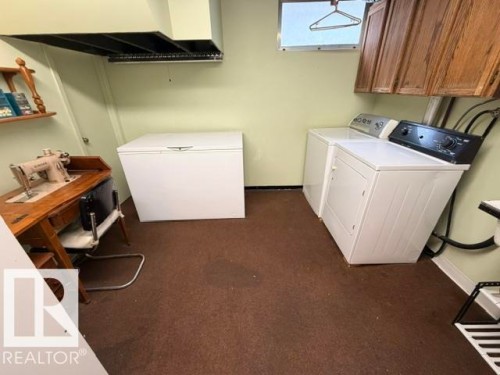 Dedicated utility space featuring brown carpeting, light green walls, a window, and wood-finish cabinetry - 6824 89 Avenue Nw, Edmonton, AB - Indoor Photo Showing Laundry Room