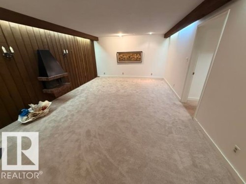 Spacious room featuring a prominent wood-paneled accent wall with integrated ambient lighting - 6824 89 Avenue Nw, Edmonton, AB - Indoor Photo Showing Other Room