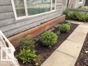 Front exterior featuring horizontal siding, a white-framed window, and a brick planter - 6824 89 Avenue Nw, Edmonton, AB  - Outdoor 