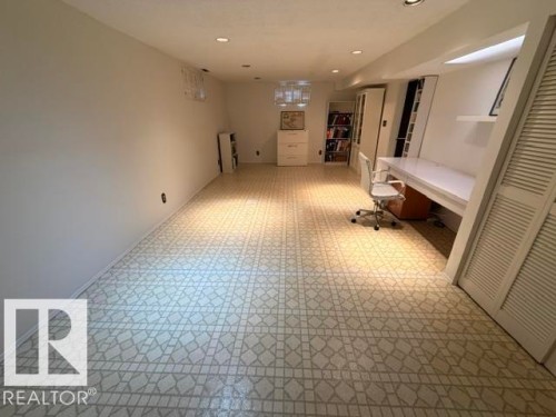 Spacious room featuring patterned flooring, recessed lighting, white walls, built-in shelving, and a built-in desk area - 6824 89 Avenue Nw, Edmonton, AB - Indoor Photo Showing Other Room