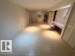 Spacious room featuring patterned flooring, recessed lighting, white walls, built-in shelving, and a built-in desk area - 