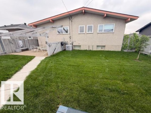 Expansive backyard featuring a concrete patio, a wooden pergola structure, and a manicured lawn - 6824 89 Avenue Nw, Edmonton, AB - Outdoor