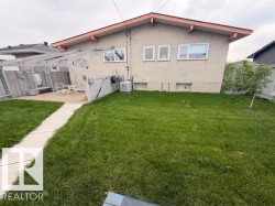 Expansive backyard featuring a concrete patio, a wooden pergola structure, and a manicured lawn - 