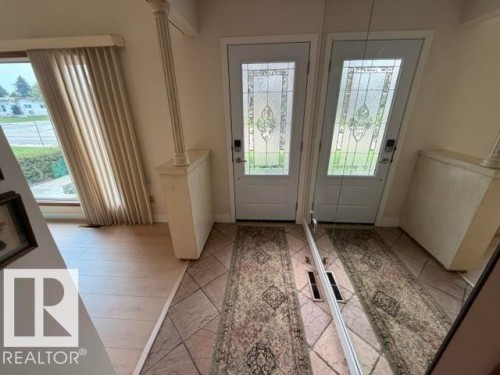 Entryway featuring a white door with decorative leaded glass, tile flooring, and wood-finish flooring - 6824 89 Avenue Nw, Edmonton, AB - Indoor Photo Showing Other Room