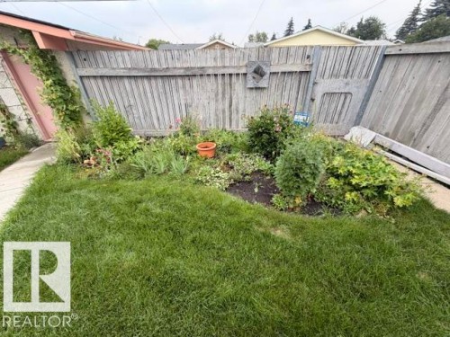 Lawn area with established garden beds and perimeter fencing - 6824 89 Avenue Nw, Edmonton, AB - Outdoor