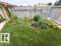 Lawn area with established garden beds and perimeter fencing - 
