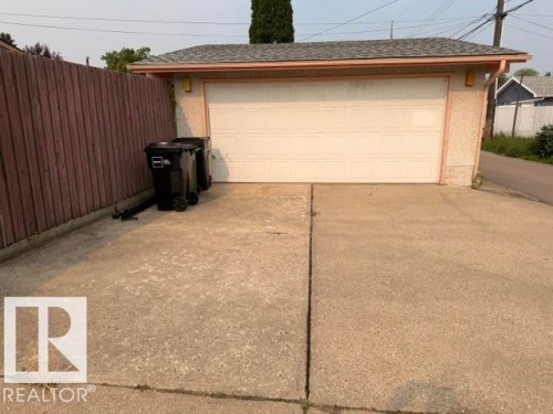 Detached garage featuring a paneled door, stucco exterior, and asphalt shingle roof - 6824 89 Avenue Nw, Edmonton, AB - Outdoor With Exterior