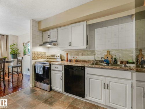 Kitchen featuring white cabinetry, tile flooring, and stone-look countertops - 13405 40 St Nw, Edmonton, AB - Indoor Photo Showing Kitchen With Double Sink With Upgraded Kitchen