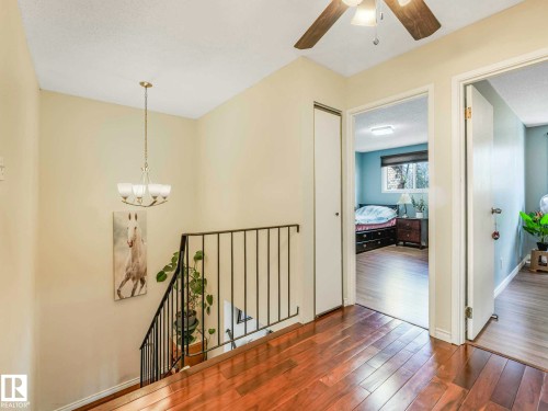 Upper-level landing featuring wood-finish flooring, a contemporary chandelier, and a ceiling fan - 13405 40 St Nw, Edmonton, AB - Indoor Photo Showing Other Room