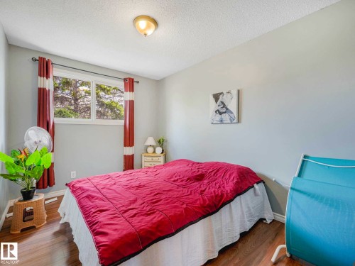 Bedroom featuring wood-finish flooring, a white trim baseboard, and a double-pane window - 13405 40 St Nw, Edmonton, AB - Indoor Photo Showing Bedroom