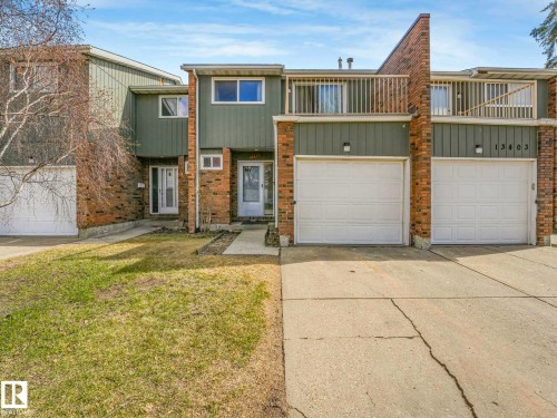 Townhome exterior featuring brick and vertical siding, attached garage, concrete driveway, and front entryway - 13405 40 St Nw, Edmonton, AB - Outdoor