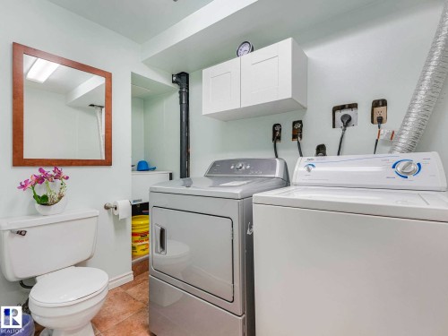 Laundry area with a white washing machine, stacked dryer, and overhead white cabinetry - 13405 40 St Nw, Edmonton, AB - Indoor Photo Showing Laundry Room