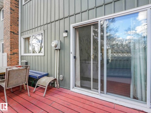 Expansive outdoor deck featuring red-painted wood planks and a white-framed sliding glass door - 13405 40 St Nw, Edmonton, AB - Outdoor With Exterior