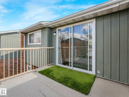 Outdoor balcony featuring concrete flooring, a sliding glass door, white railing, and exterior wall paneling - 13405 40 St Nw, Edmonton, AB - Outdoor With Exterior