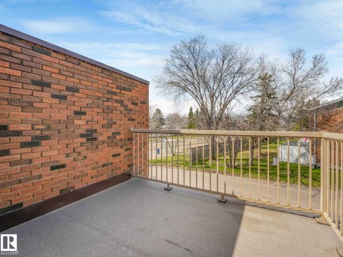 Private outdoor balcony featuring a neutral-toned metal railing, a textured dark gray surface, and a brick exterior wall - 13405 40 St Nw, Edmonton, AB - Outdoor With Balcony
