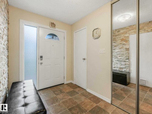 Entryway featuring a white door with an arched glass insert, a frosted sidelight, and square tile flooring - 13405 40 St Nw, Edmonton, AB - Indoor Photo Showing Other Room