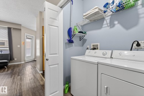 Dedicated laundry area with side-by-side appliances, overhead wire shelving, and a wall-mounted utility shelf - #103 8108 109 St Nw, Edmonton, AB 