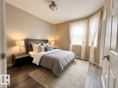 Warm neutral wall tones, wood-finish flooring, two large windows, and a classic ceiling fixture - #103 8108 109 St Nw, Edmonton, AB 
