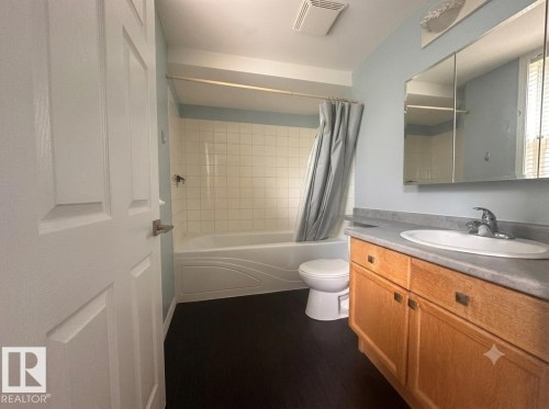 Full bathroom featuring a single vanity, integrated sink, and wood-finish cabinetry - #103 8108 109 St Nw, Edmonton, AB 