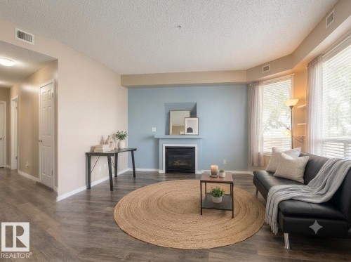 Wood-finish flooring, built-in fireplace, bay windows, and light-toned walls - #103 8108 109 St Nw, Edmonton, AB 
