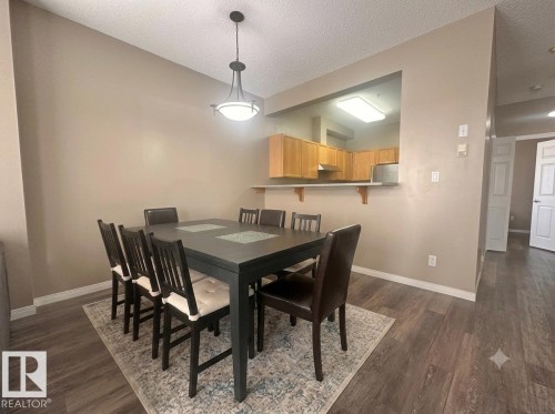 Wood-finish flooring throughout, with a pass-through window and a built-in breakfast bar in the kitchen - #103 8108 109 St Nw, Edmonton, AB 