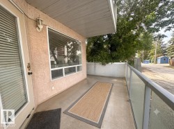 Private balcony featuring a glass panel railing, concrete flooring, and an exterior wall light - 
