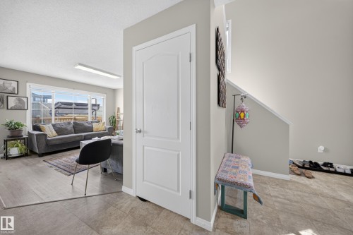 Living area with light wood-finish flooring, large windows, and a flush-mount ceiling light - 1927 51 Street Sw, Edmonton, AB - Indoor Photo Showing Other Room