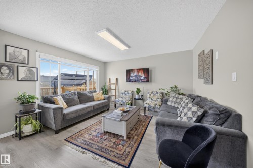 Spacious living area featuring light gray walls, wood-finish flooring, and a large sliding glass door - 1927 51 Street Sw, Edmonton, AB - Indoor Photo Showing Living Room