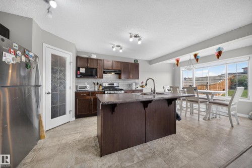 Kitchen featuring rich wood-finish cabinetry, a central island with a sink, stainless steel appliances, and tile flooring - 1927 51 Street Sw, Edmonton, AB - Indoor Photo Showing Kitchen With Stainless Steel Kitchen With Upgraded Kitchen