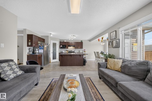 Open concept living area featuring wood-finish flooring, recessed lighting, and a glass sliding door - 1927 51 Street Sw, Edmonton, AB - Indoor Photo Showing Living Room