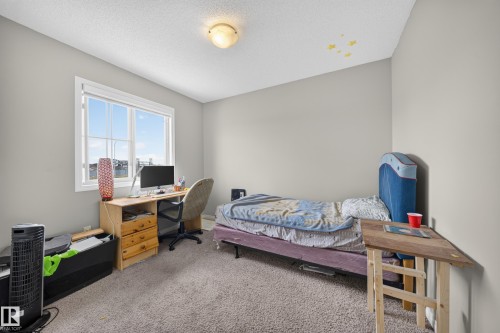 Carpeted room with a large window, light gray walls, and a ceiling-mounted light fixture - 1927 51 Street Sw, Edmonton, AB - Indoor Photo Showing Bedroom