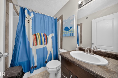 Vanity with an integrated sink, a two-handle faucet, and a dark stone-finish countertop - 1927 51 Street Sw, Edmonton, AB - Indoor Photo Showing Bathroom
