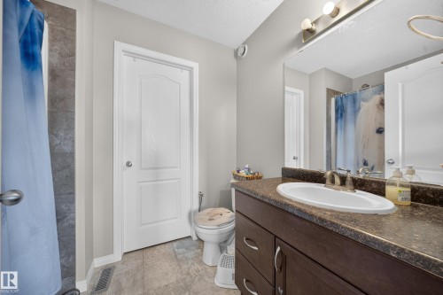 Vanity with an integrated sink, dark wood-finish cabinetry, and a full-width mirror - 1927 51 Street Sw, Edmonton, AB - Indoor Photo Showing Bathroom