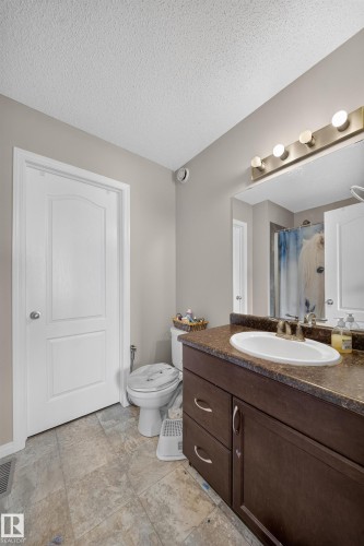 Vanity with a built-in sink, dark wood-finish cabinetry, and a textured countertop - 1927 51 Street Sw, Edmonton, AB - Indoor Photo Showing Bathroom
